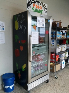 A community food sharing refrigerator with a glass door, labeled 